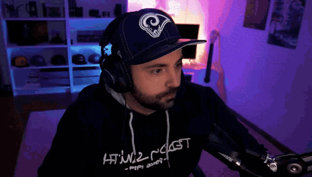 a man wearing a rams hat and headphones looks at the camera