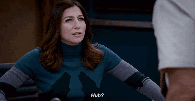 a woman wearing a turtleneck sweater with a wolf on it says huh