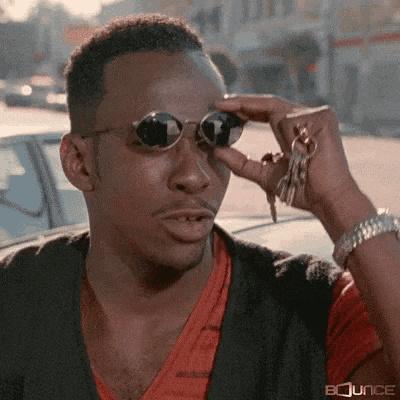 a man wearing sunglasses and holding a bunch of keys is standing in front of a car .