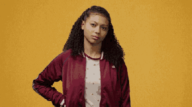 a woman wearing a maroon champion jacket makes a funny face