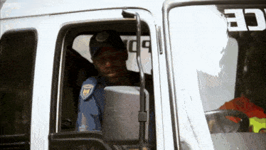 a man in a blue hat is sitting in the driver 's seat of a truck that says bbc