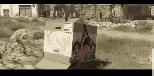 a cardboard box with graffiti on it is sitting in the grass