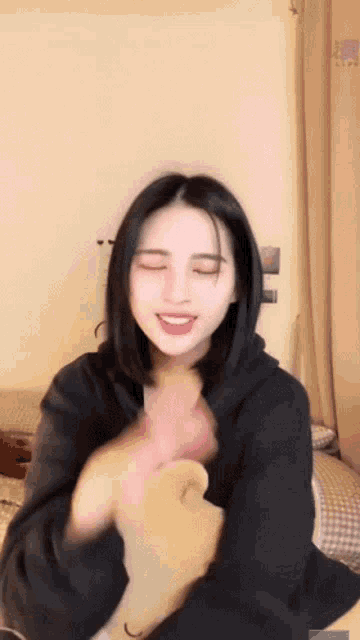a woman in a black sweatshirt is making a funny face with her eyes closed
