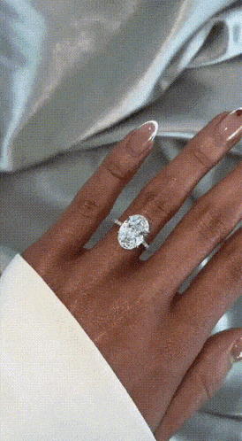 a close up of a woman 's hand with a diamond ring on her finger .