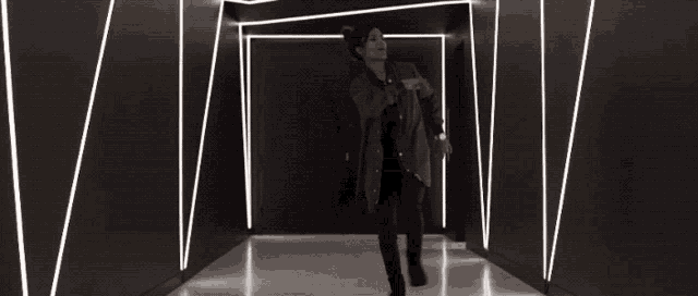a man is dancing in a dark hallway with lights on the wall