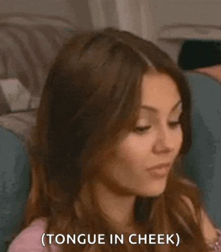 a woman is sitting on a couch with her mouth open and the words tongue in cheek .