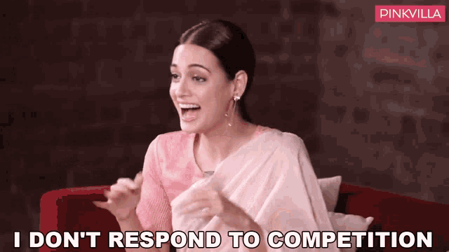 a woman is sitting on a red couch and says " i don t respond to competition "