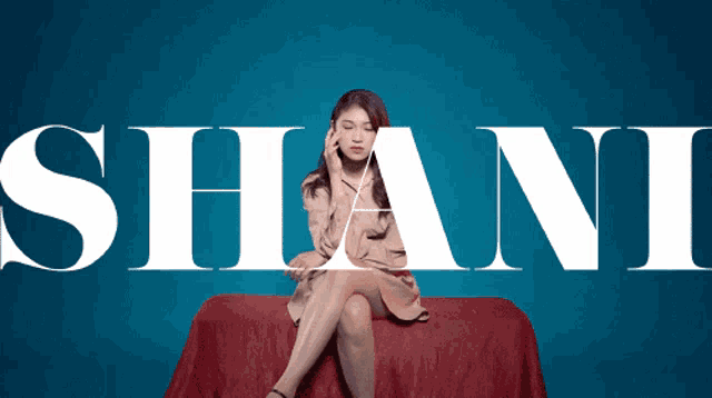 a woman sits on a red couch in front of a blue background that says shani