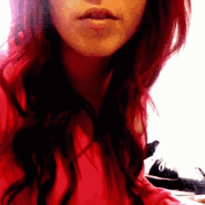 a close up of a woman 's face with red hair wearing a red shirt