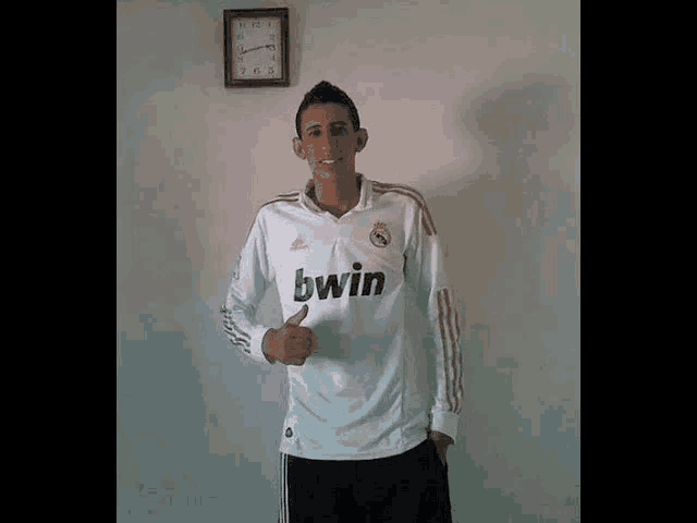 a young man wearing a white bwin jersey gives a thumbs up