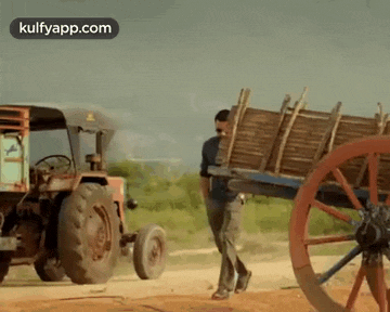 a man is pushing a wooden cart behind a tractor .