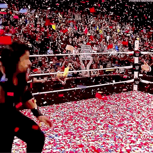 a man is standing in a wrestling ring surrounded by confetti and a crowd .