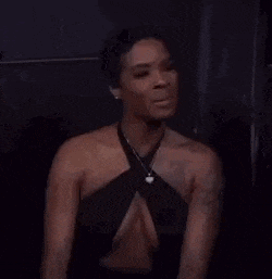 a woman in a very revealing black dress is sitting in a dark room .