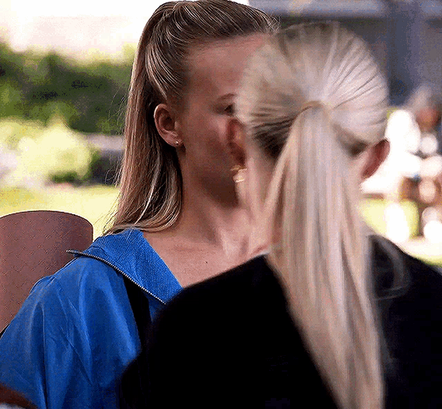 two women are standing next to each other and one of them is wearing a blue jacket .