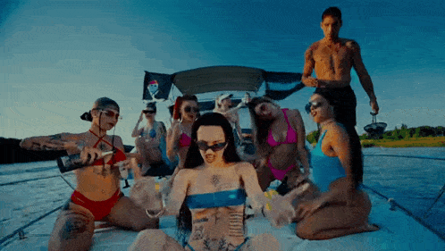 a group of women in bikinis are sitting on a boat in the water .