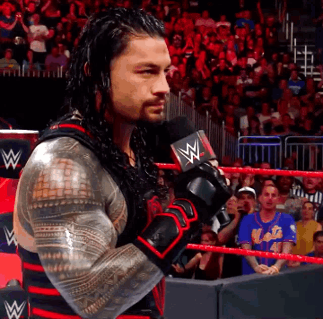 a man in a wrestling ring is holding a microphone with a w on it