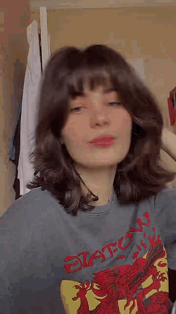 a girl with short hair and bangs is wearing a gray t-shirt .