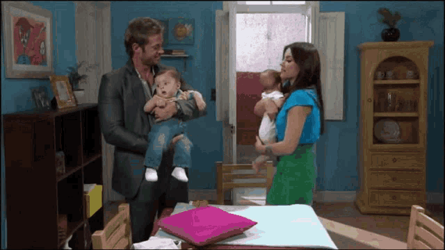 a man and a woman holding a baby in a living room