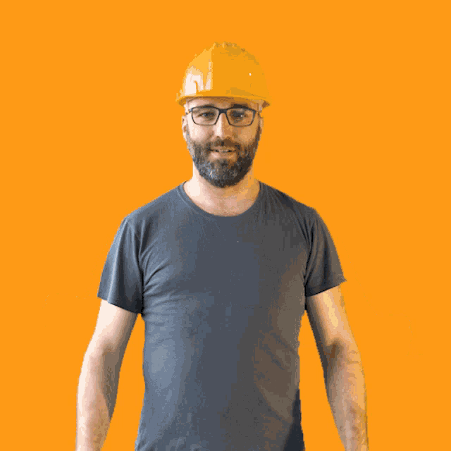 a man wearing a hard hat and glasses is raising his fist