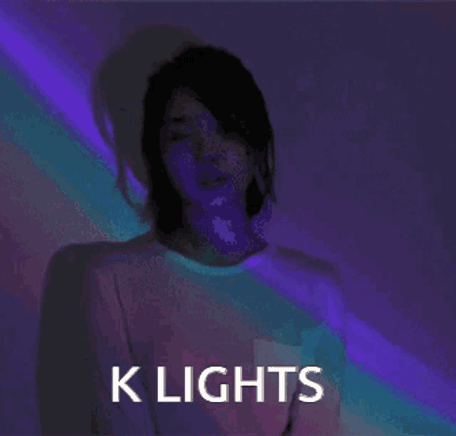 a woman is standing in front of a purple wall with the words k lights above her