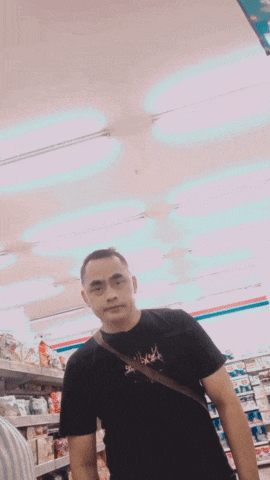 a man wearing a black shirt that says ' always ' on it stands in a store