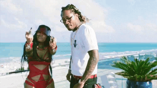 a man and woman are standing on a balcony overlooking the ocean .