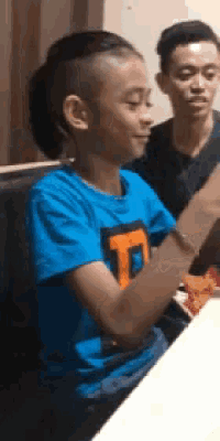 a young boy in a blue shirt with the letter t on it