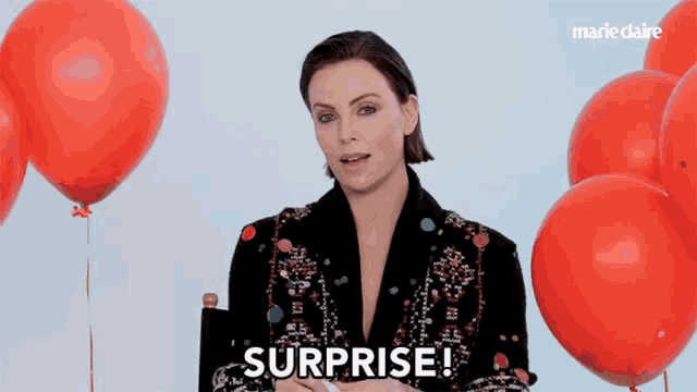 a woman says surprise in front of balloons
