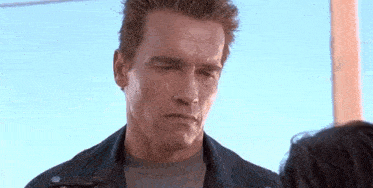 a man in a leather jacket is looking at a woman in a gray shirt .