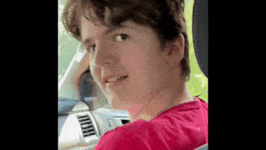 a young man is sitting in the back seat of a car looking at the camera .