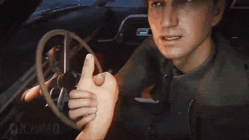 a man is sitting in a car holding a steering wheel and looking at the camera .
