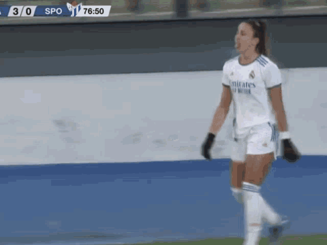 a female soccer player wearing a white emirates jersey is walking on the field .