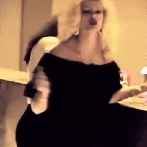 a woman in a black dress is standing in a room .