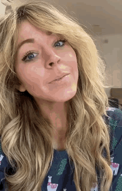 a woman wearing a blue shirt with llamas on it looks at the camera
