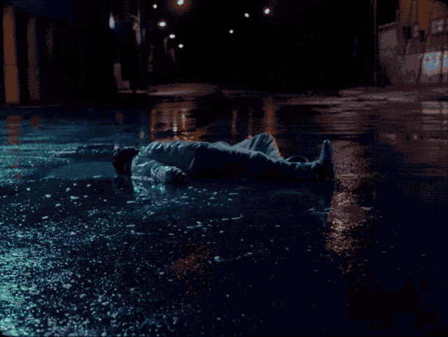 a person is laying in a puddle of water at night