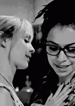 a black and white photo of two women looking at each other . one of the women is wearing glasses .