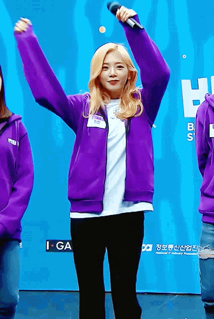 a woman in a purple jacket holding a microphone