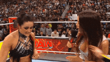 two women are standing in a wrestling ring with the word raw on the wall