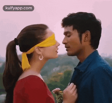 a man and a woman are kissing with their eyes covered with a yellow bandage .
