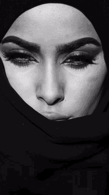 a black and white photo of a woman 's face with a hijab on