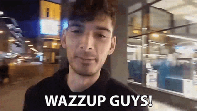 a man says wazzup guys in front of a building at night