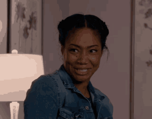 a woman in a denim jacket is smiling and looking at the camera