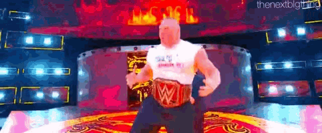 a man is standing on a stage with a wrestling belt on his waist .
