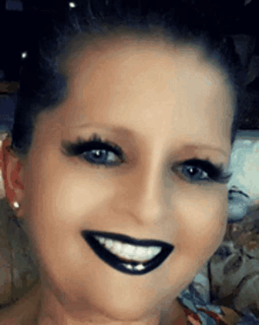 a close up of a woman 's face with black lipstick on her lips