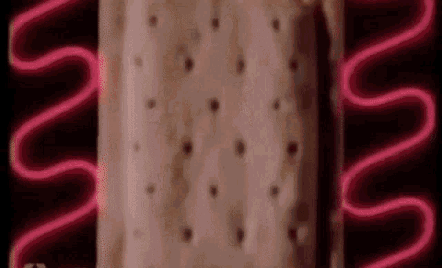 a close up of a pink ice cream sandwich with a neon light behind it .
