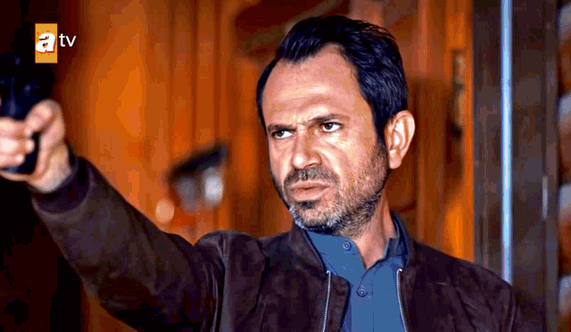a man holds a gun in front of a tv logo