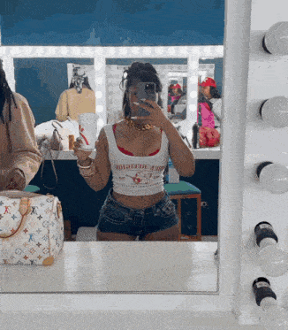 a woman is taking a selfie in front of a mirror wearing a true religion shirt