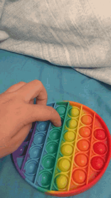 a person playing with a rainbow colored pop it