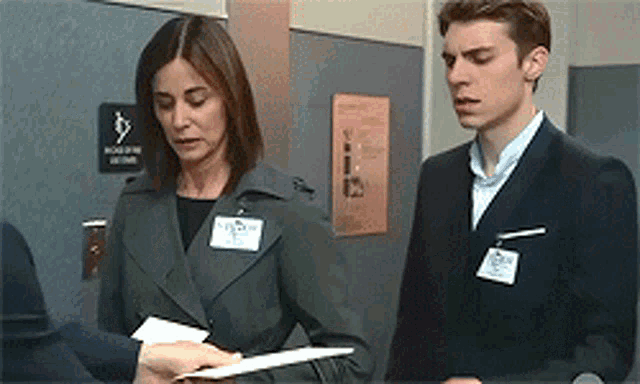 a man and a woman are standing next to each other in front of a sign that says no smoking in this room