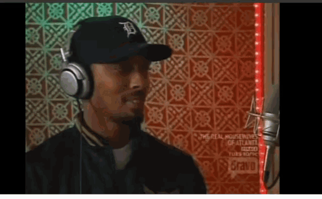a man wearing headphones and a black hat with the letter d on it